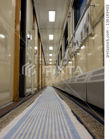 Train journey corridor presenting empty pathway with blue striped runner carpet Train journey corridor presenting empty pathway with blue striped runner carpet 136169488
