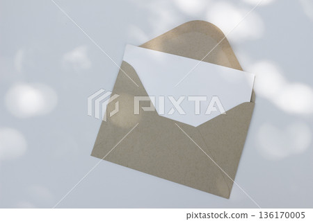 Minimal envelope mockup with blank card on white background in sunlight. Open kraft paper envelope. Invitation, natural stationery flat lay, top view. Minimal wedding, branding template, copy space Minimal envelope mockup with blank card on white background in sunlight. Open kraft paper envelope. Invitation, natural stationery flat lay, top view. Minimal wedding, branding template, copy space 136170005