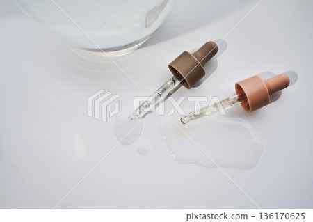 Skincare product droppers with spilled serum on studio background 136170625