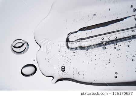 Clear cosmetic serum dripping with glass pipette 136170627