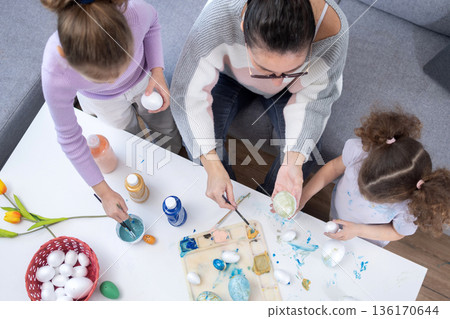 Mother and two daughters painting Easter eggs Mother and two daughters painting Easter eggs 136170644