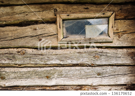 Old weathered wooden wall with small window showing signs of decay 136170652