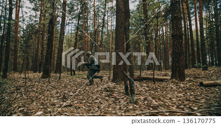 German soldier running with rifle through forest during WWII reenactment 136170775