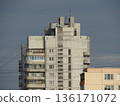 A tall urban building with many windows. The building is gray, and there are many wires hanging from it. A residential apartment building 136171072