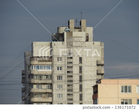 A tall urban building with many windows. The building is gray, and there are many wires hanging from it. A residential apartment building 136171072