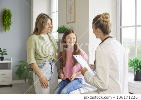 Mother and daughter at pediatric checkup with female doctor in bright clinic 136171226