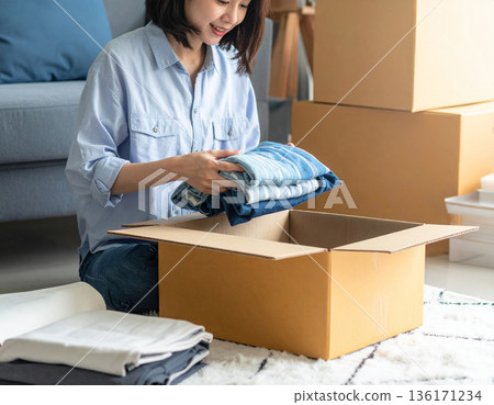一位婦女將衣物打包進紙箱，準備開始她的新生活 136171234