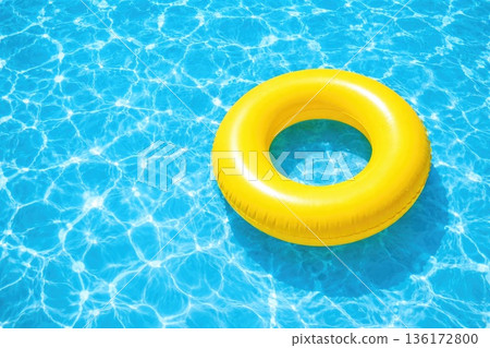 Bright yellow inflatable swim ring floating in clear blue swimming pool water 136172800
