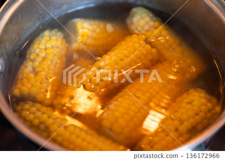 Close up of boiling corn in a pot. Fresh young corn boiling in a pot on stove, fresh tasty corn Close up of boiling corn in a pot. Fresh young corn boiling in a pot on stove, fresh tasty corn 136172966