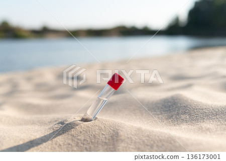 Testing water of river beach. Laboratory test tube on sand on river beach in sunny day 136173001