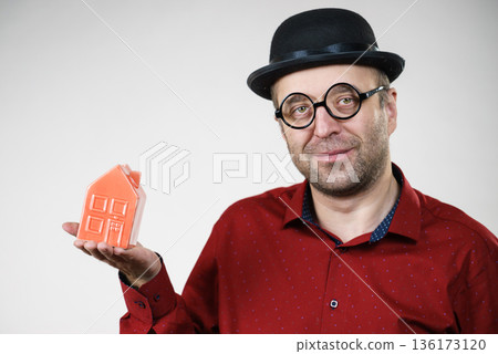 Man wearing funny eyeglasses holding house Man wearing funny eyeglasses holding house 136173120