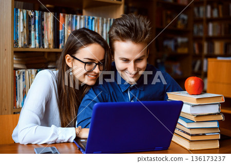 Male and female students working together in the library, looking for information in books and the Internet, eager to study and become more intelligent. Students learning 136173237