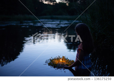 Young girl with wreath going to the river to set it float down the river, kapala night magic, pagan traditions. Girl swims in river late at night Young girl with wreath going to the river to set it float down the river, kapala night magic, pagan traditions. Girl swims in river late at night 136173250