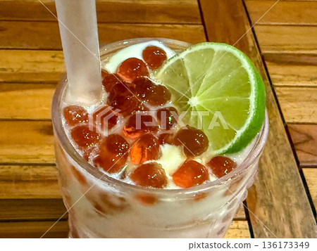 Iced creamy cocktail with lime and tapioca pearls on wooden table Iced creamy cocktail with lime and tapioca pearls on wooden table 136173349