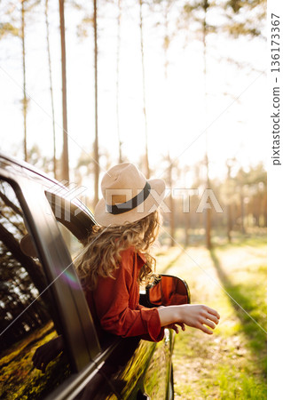 Young woman leaning out of the car window enjoying nature. Road trips summer holidays. Young woman leaning out of the car window enjoying nature. Road trips summer holidays. 136173367