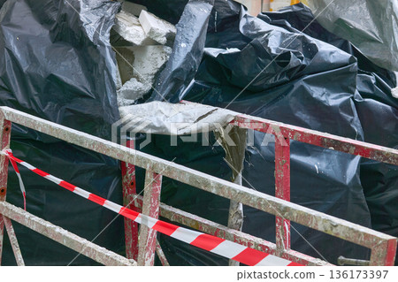 Cleaning.Metal red fencing,polypropylene filled bags with garbage Cleaning.Metal red fencing,polypropylene filled bags with garbage 136173397