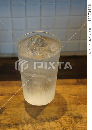 top view A glass of cold water sits on a wooden floor and a white tiled wall background, cool, ice, fresh, copy space top view A glass of cold water sits on a wooden floor and a white tiled wall background, cool, ice, fresh, copy space 136173446