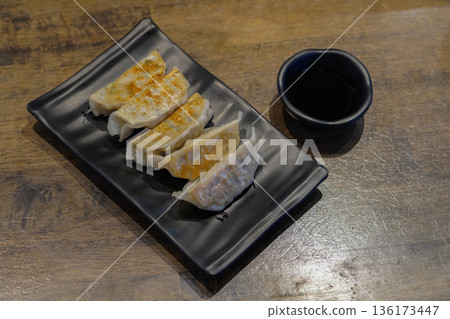 top view five gyoza in a black ceramic plate and sauce in a black ceramic cup on wooden floor background, food, snack, decor, fashion, copy space 136173447