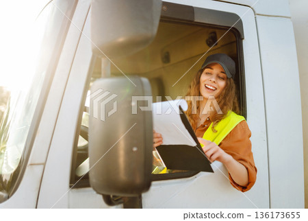Portrait of woman truck driver in casual clothes standing in front of truck. Transport industry Portrait of woman truck driver in casual clothes standing in front of truck. Transport industry 136173655