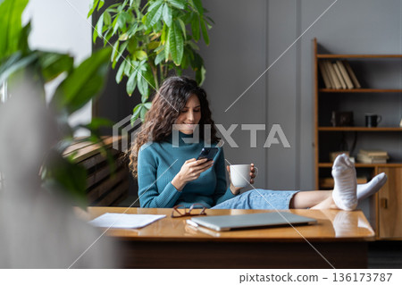 Smartphone addiction at work. Female employee with smartphone enjoying rest break during workday 136173787
