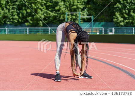 African American woman with long braids bends down doing effective exercise for stretching body African American woman with long braids bends down doing effective exercise for stretching body 136173788
