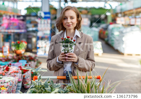 Woman with shopping trolley choosing floral plants for home 136173796