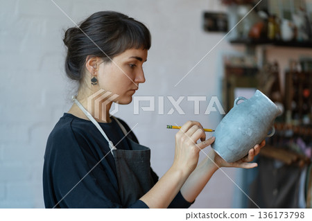 Concentrated female examines her manufactured product, comes up with individual design for art shop. 136173798