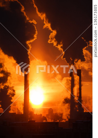 Coal-fired power station with smoking chimneys against red sunset sky. Air pollution in winter city 136173805