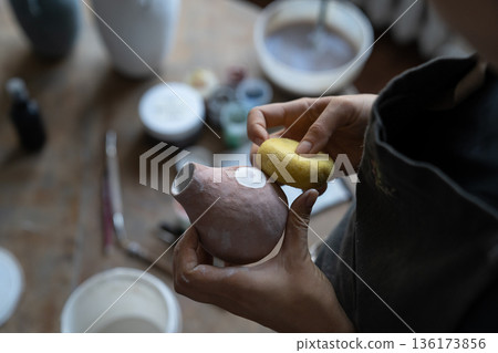 Young girl artisan busy with modelling jug vase from clay while pottery lesson or workshop in studio Young girl artisan busy with modelling jug vase from clay while pottery lesson or workshop in studio 136173856
