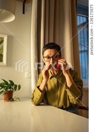 Senior worried woman giving away credit card information, talking to manipulators on smartphone. 136173875