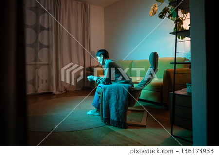 Upset senior woman with lost expression sitting alone in living room dealing with personal drama. 136173933