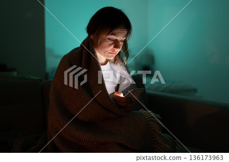 Sleepy woman sitting on couch using smartphone late at night, can not sleep. Insomnia, addiction. Sleepy woman sitting on couch using smartphone late at night, can not sleep. Insomnia, addiction. 136173963