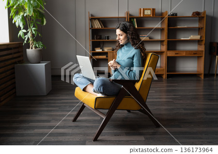 Female consultant in headset consulting remotely via laptop from home, having video chat with client Female consultant in headset consulting remotely via laptop from home, having video chat with client 136173964
