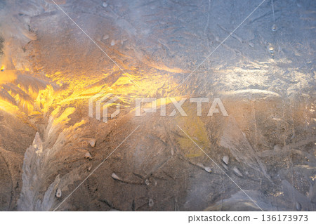 Natural frosty iced pattern formation with texture cracks on frozen window glass in winter season. Natural frosty iced pattern formation with texture cracks on frozen window glass in winter season. 136173973