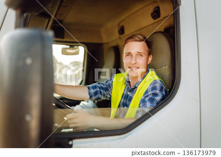 Driver at the wheel of a truck at work. Driver or forwarder on truck on a transshipment point 136173979