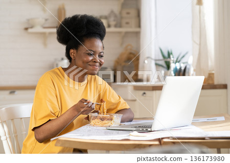 African female eat and watch video or webinar on laptop or make conference call to friends on break African female eat and watch video or webinar on laptop or make conference call to friends on break 136173980