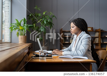 Focused business black woman in suit remote book keeper preparing financial report on laptop 136174057