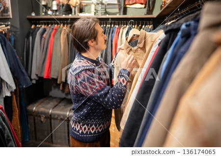 Trendy hipster second hand lover picking clothes in vintage resale store, conscious consumption. 136174065