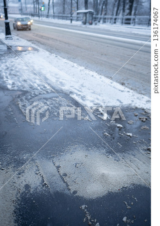 Deicing chemicals on snowy street in winter. Slippery road sprinkled with technical salt 136174067
