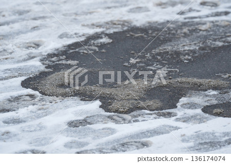 Deicing chemicals on street in winter. Slippery road sprinkled with technical salt. Prevent slipping 136174074