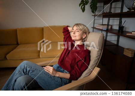 Tranquil relaxed middle aged woman resting at home in comfy chair, dreaming enjoying calm moments. Tranquil relaxed middle aged woman resting at home in comfy chair, dreaming enjoying calm moments. 136174080