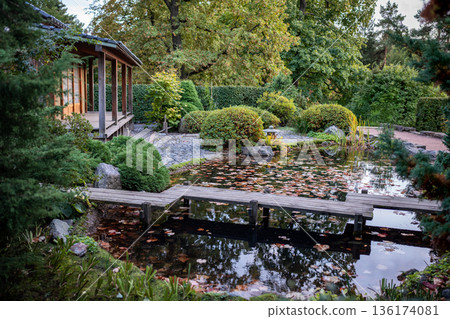 Traditional Japanese tea house with pond, wooden bridge, garden with stones and green bushes Traditional Japanese tea house with pond, wooden bridge, garden with stones and green bushes 136174081