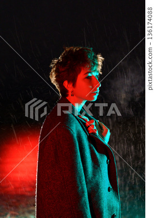 Frightened woman is freezing standing on street in snowy weather throwing coat over shoulders Frightened woman is freezing standing on street in snowy weather throwing coat over shoulders 136174088