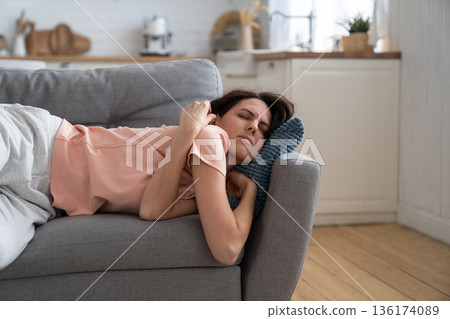 Woman with closed eyes lying on pillow resting trying to sleep in uncomfortable pose on sofa at home Woman with closed eyes lying on pillow resting trying to sleep in uncomfortable pose on sofa at home 136174089