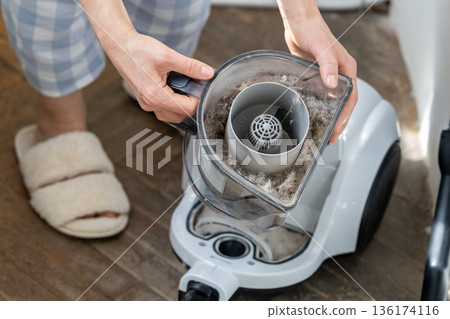 Female opening dust filter out of vacuum cleaner at home, hoover container full of dirt, pet hair Female opening dust filter out of vacuum cleaner at home, hoover container full of dirt, pet hair 136174116