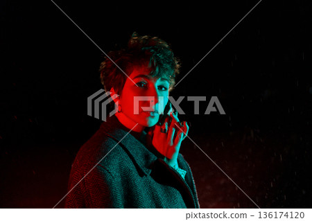 Frozen Caucasian woman as with coat draped over shoulders posing standing on street at night Frozen Caucasian woman as with coat draped over shoulders posing standing on street at night 136174120
