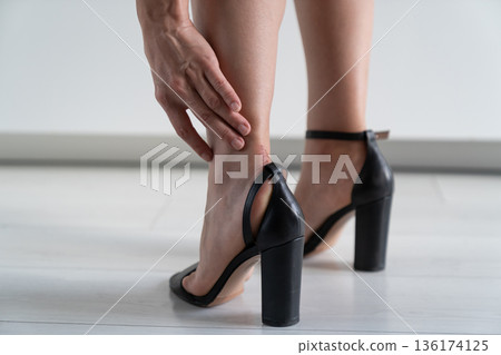 Woman feet in pain after wearing high heeled shoes after walking, takes off tight shoes closeup. Woman feet in pain after wearing high heeled shoes after walking, takes off tight shoes closeup. 136174125
