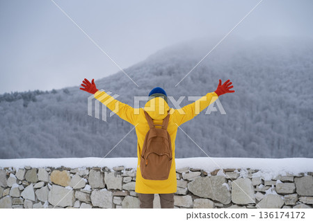 Carefree man with hands outstretched to side looks at snowy mountain feels freedom, harmony nature. Carefree man with hands outstretched to side looks at snowy mountain feels freedom, harmony nature. 136174172