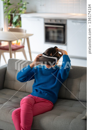 Young woman puts on VR glasses for first time and prepares to play interesting games at home 136174184