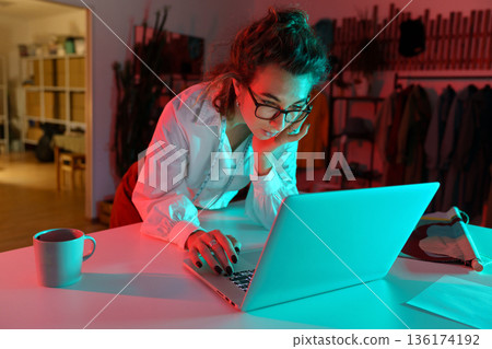 Young female clothes designer work on laptop in atelier studio read business email and making orders 136174192